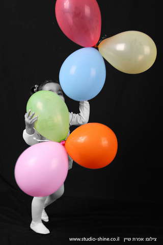 ילדת יום ההולדת אוחזת בבלונים צבעוניים